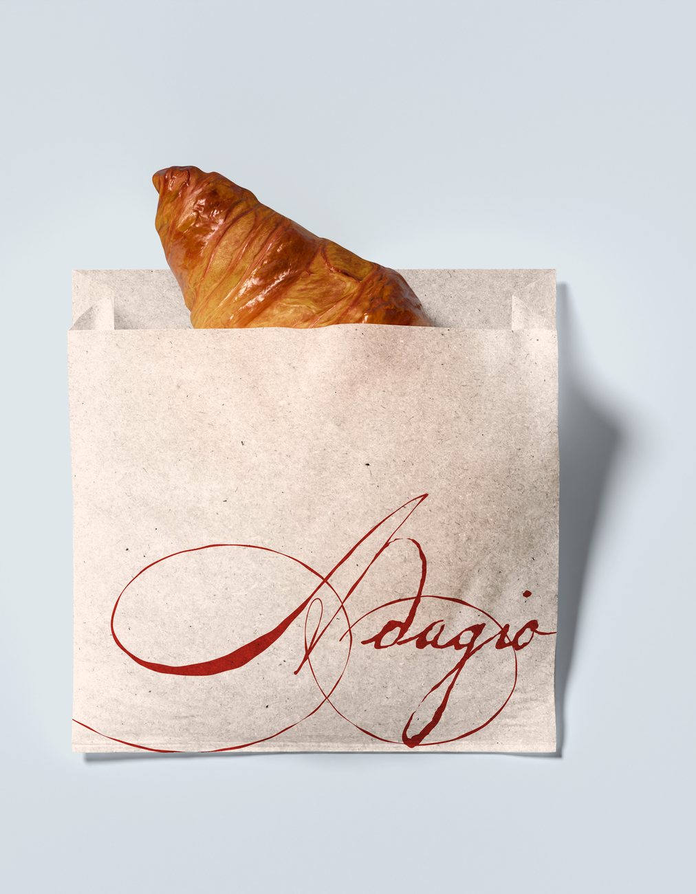 Adagio paper bag holding a croissant