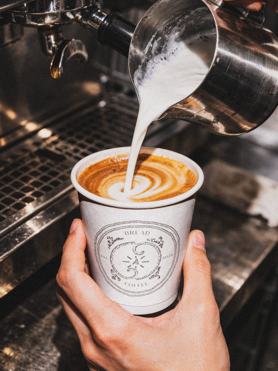 Adagio branded coffee cup with a latte pour